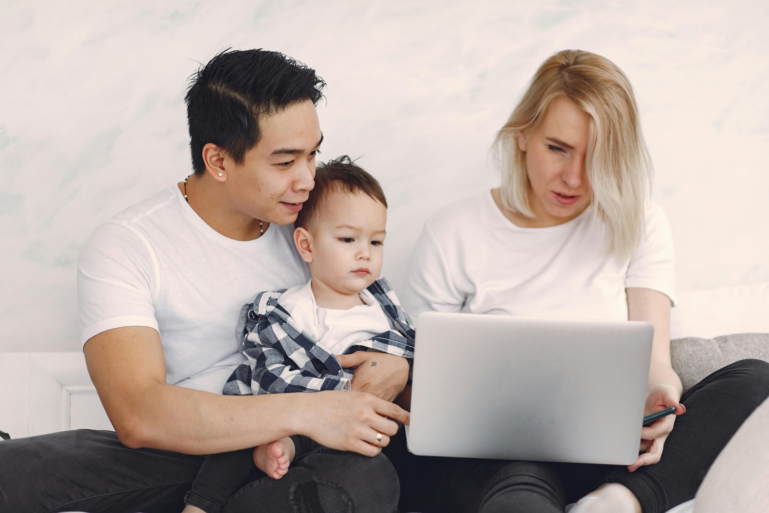 Young family enjoying quality time together, engaging with a laptop indoors.