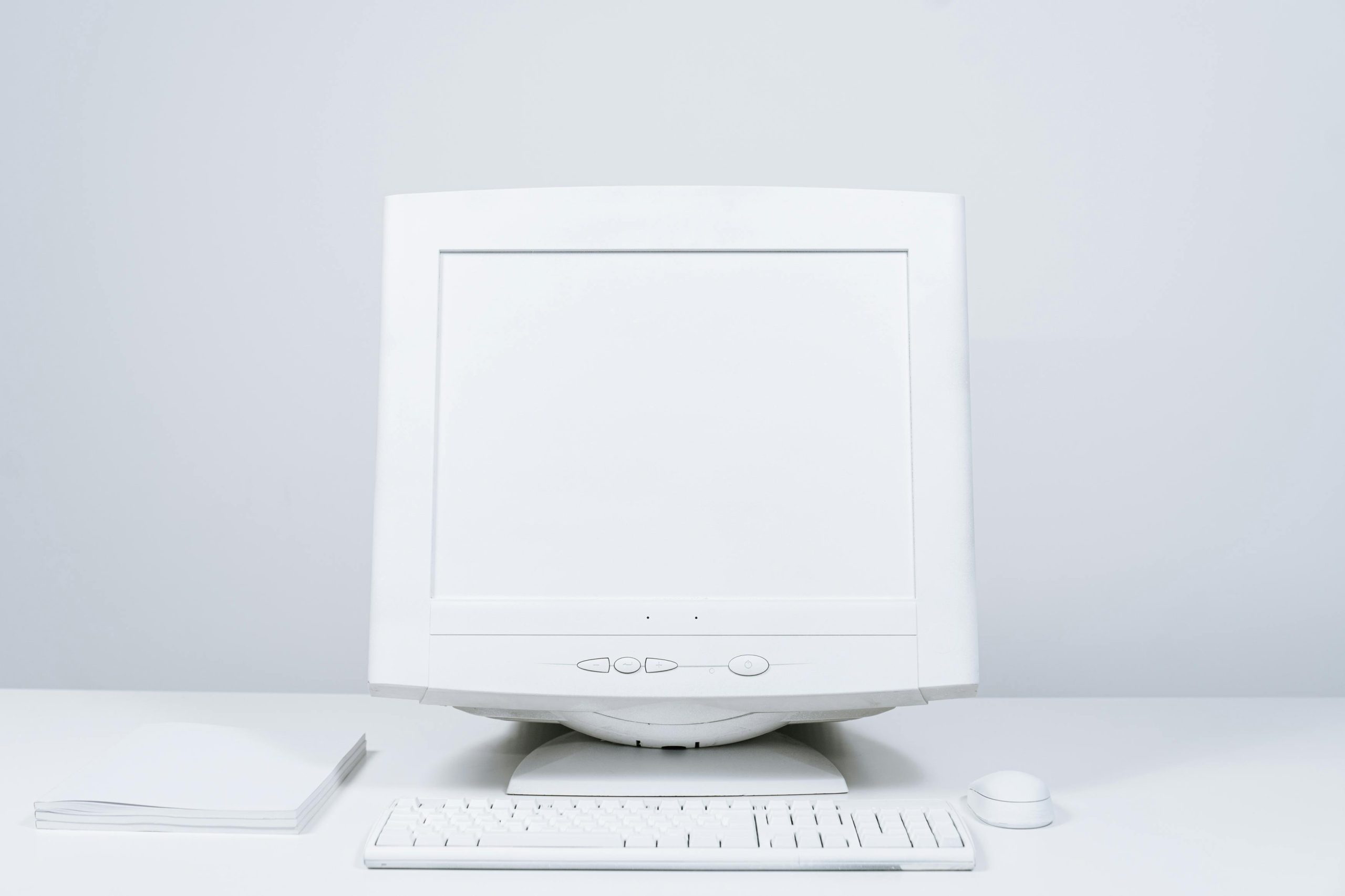 A minimalist white computer setup including monitor, keyboard, and mouse on desktop.